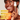 Woman holding an orange and a skincare product with KOA LIFE branding, against a neutral background.