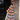 Person wearing a colorful crochet coat standing against a stone wall.