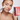 Woman applying blush with a brush and palette on a plain background