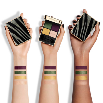 Three hands holding Guerlain eyeshadow palettes with color swatches on arms