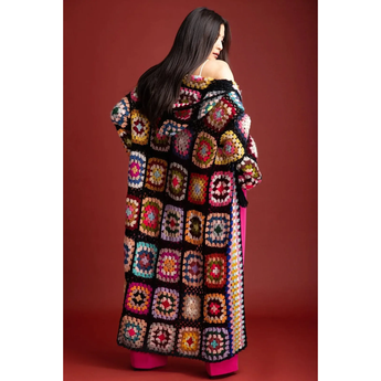 Woman wearing a colorful crochet coat against a red background